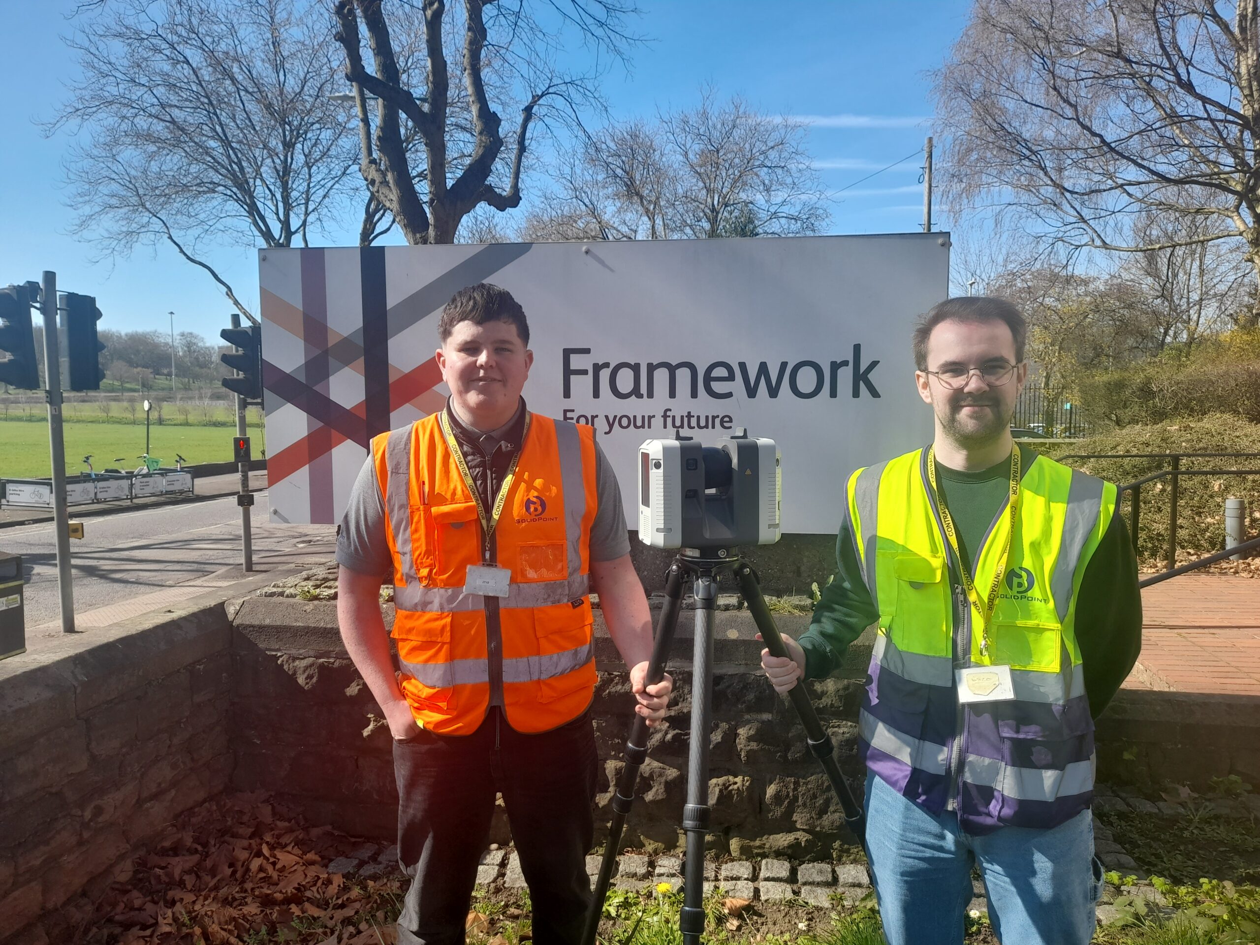 Two SolidPoint surveyors in front of a Framework Housing Association sign